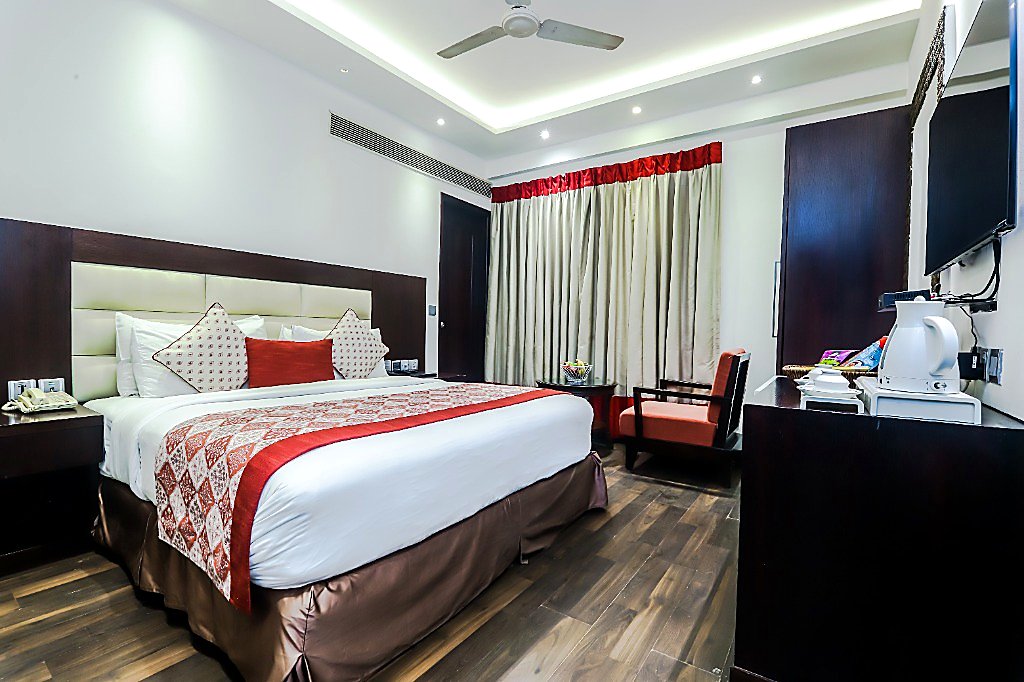 Studio Room with Air-Purifier at Hotel Grand Godwin New Delhi — spacious 275 sq.ft layout, double bed, rich mahogany decor, minibar, and city views