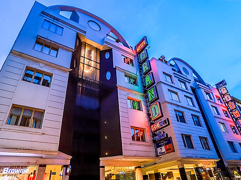 Hotel Grand Godwin building exterior facade illuminated at dusk with neon sign, Cafe Brownie, and entrance in Paharganj New Delhi